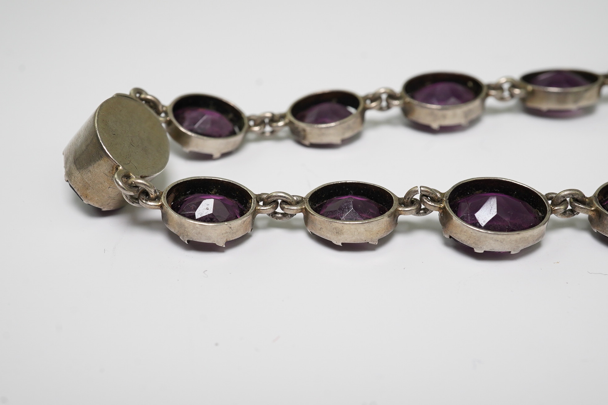 A Victorian silver and graduated oval cut amethyst paste set riviere necklace